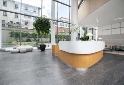 Bright reception area with a curved wooden desk and views of an outdoor green courtyard.