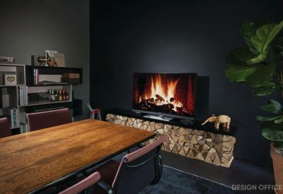 Meeting room with a wooden table, leather chairs, and a digital screen showing a fireplace.