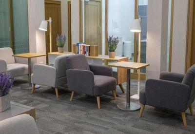 Lounge area with grey armchairs, wooden side tables, and lavender plants.