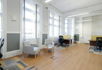 Bright open-plan office space with wooden floors and several workstations.