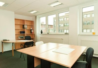 Spacious sunlit office with two large wooden desks and shelving units.