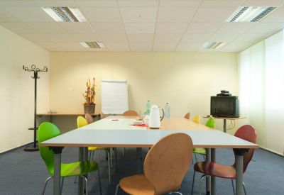 Functional meeting room with a large table and colorful green and orange chairs.
