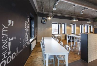 Spacious breakout area with a long white table and graphic typography on a black wall.