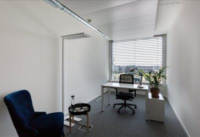 Private office suite with a blue armchair, white desk, and natural light.