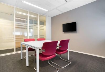Small meeting room with four pink chairs, a white table, and a wall-mounted television screen.