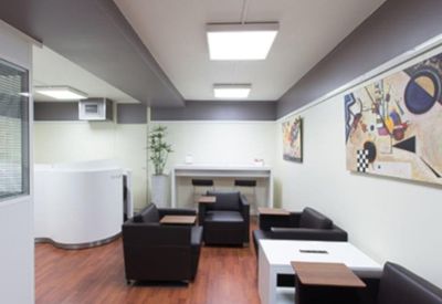 Communal lounge area with black leather armchairs and abstract wall art.