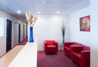 Reception area featuring red armchairs, a blue vase, and colorful wall art.