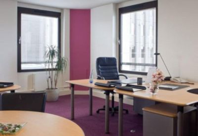 Private office suite with two wooden desks, a purple carpet, and natural light.
