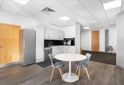 Kitchen and breakout area with a white table, grey chairs, and a sleek kitchenette.