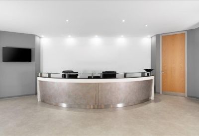 Modern reception desk with a metallic curved front and bright overhead lighting.