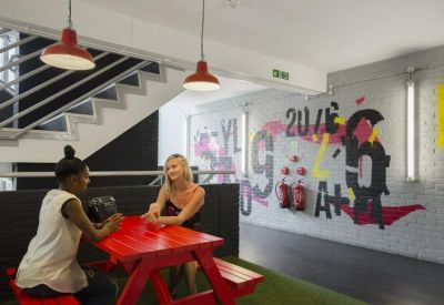 Bright communal breakout area featuring a red picnic table and vibrant mural art.