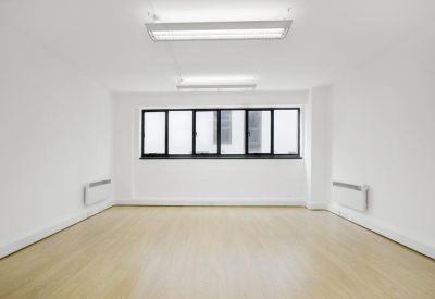 Bright, empty open-plan office space with light wood flooring and large windows.