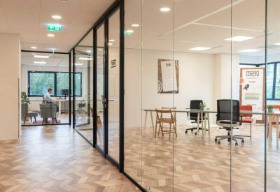 Bright glass-enclosed meeting room with herringbone wood floors and natural light.