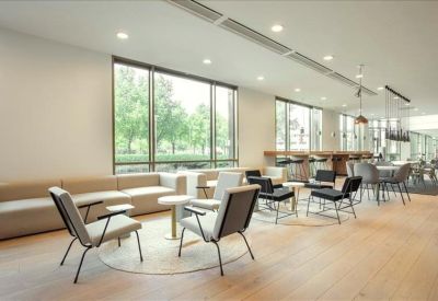 Sunny lounge area with plush sofas, modern armchairs, and floor-to-ceiling windows.