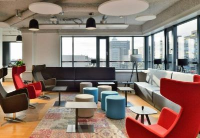 Vibrant breakout lounge with red wingback chairs, blue ottomans, and large windows.