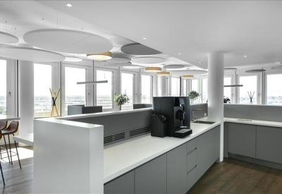 Modern breakout kitchen area with a sleek grey counter and coffee machine.