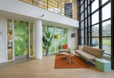 Bright double-height communal lounge with a green feature wall and mezzanine level.