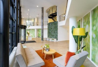 Spacious reception area with a curved green wall and stylish lounge seating.