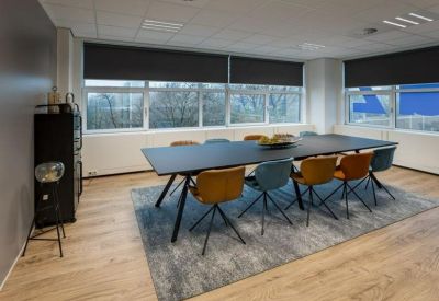 Large meeting room with a dark long table and mixed mustard and blue chairs.