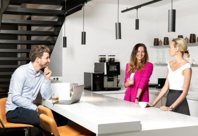 Modern office kitchen and breakout area with a white marble island and social seating.