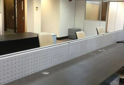 Modern workspace with long rows of dark wood desks and integrated power outlets.