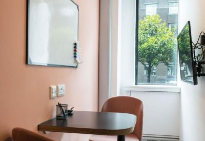 Small private office booth with a wall-mounted whiteboard and pink accent wall.