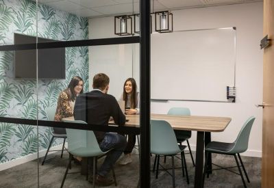 Glass-walled meeting room with leaf-patterned wallpaper and a long wooden table.