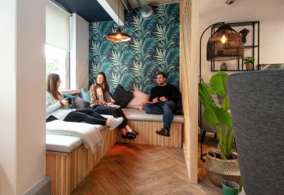 Lounge area with tropical leaf wallpaper and wooden bench seating.