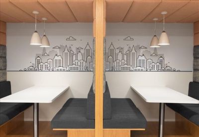 Symmetrical wooden coworking booths with grey seating and city skyline wall art.