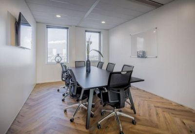 Private meeting room with a black conference table, ergonomic chairs, and whiteboard.