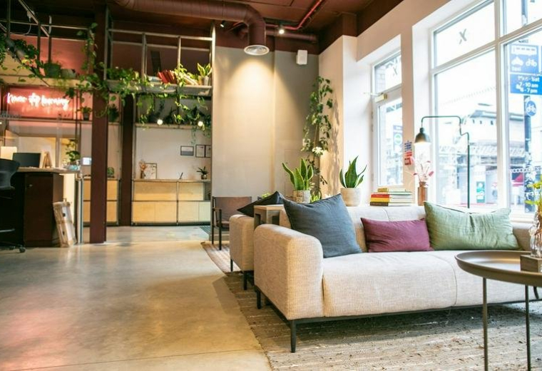 Spacious reception lounge at 20-30 Whitechapel Road with a cream sofa, colorful cushions, and large windows.