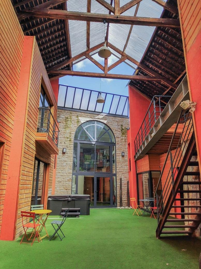 Courtyard view of 182, Rue Paul Bellamy with vibrant walls and outdoor seating.