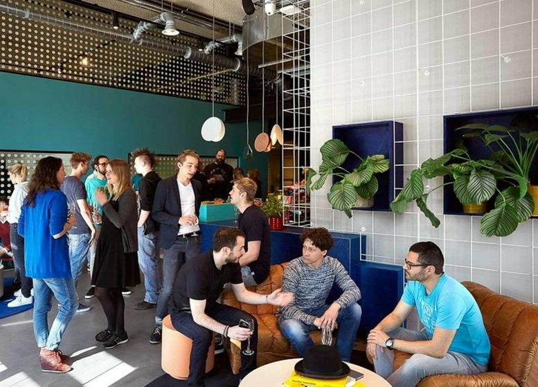 Lively communal lounge at Van Leeuwenhoekpark 1, The Social Hub Delft with colorful seating and potted plants.