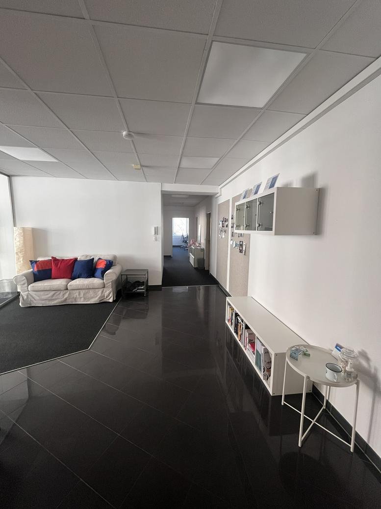 Lobby and reception area at Holzgraben 1-3 with a white sofa and reflective black floors.
