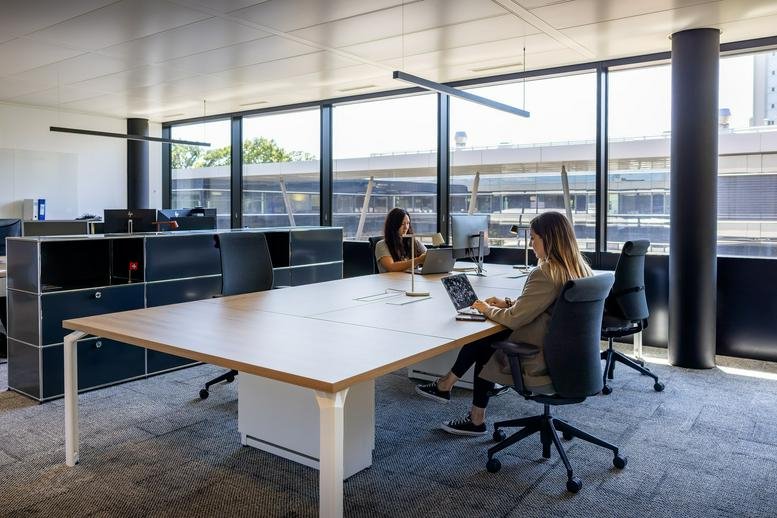 Open-plan office with desks and large windows in Klybeckstrasse 161, K-25 building.