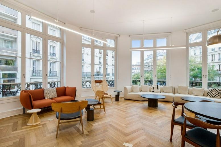 Spacious sunlit lounge at 1 Avenue de la Republique, Paris with large arched windows and parquet floors.