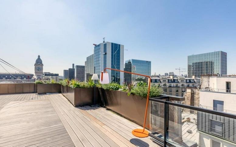 Rooftop terrace at 15-17 rue Traversière with wooden decking and views of the Paris skyline.