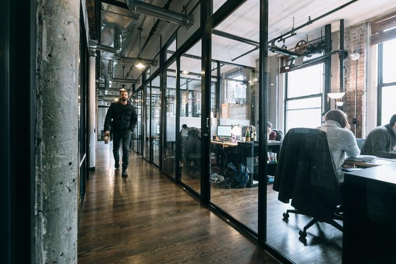 Industrial-style hallway with glass partitions and polished wood floors at 31 Rue du Commerce, Brussels.