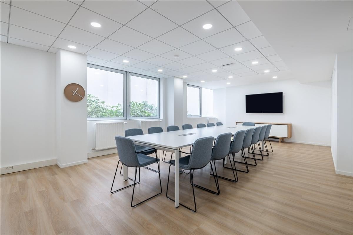 Large meeting room at 73 Rue de Vaugirard featuring a long white table and blue upholstered chairs.
