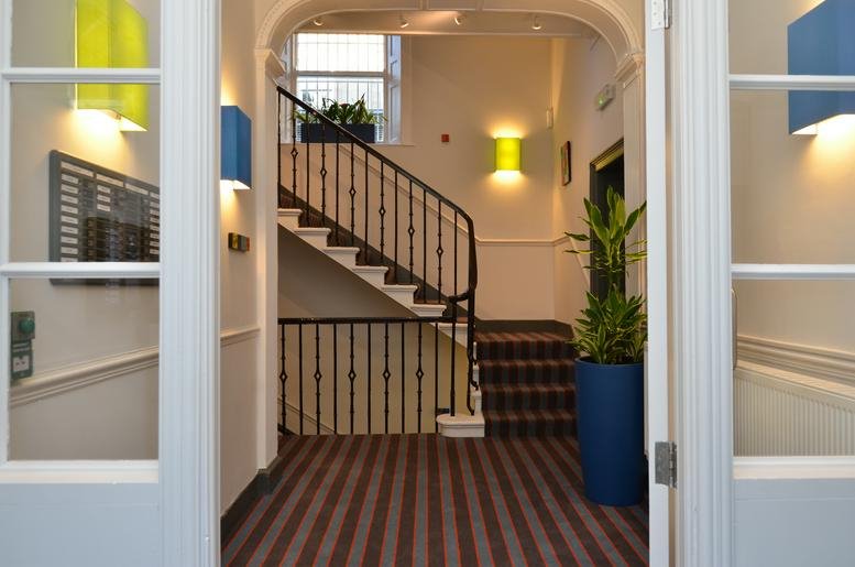 Grand hallway entrance at 21 Young Street with a sweeping staircase and vibrant wall art.