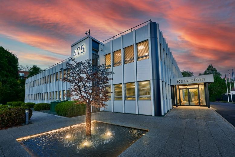 Exterior of the office building at sunset with warm lights illuminating the windows and landscaping.