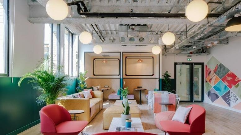 Spacious communal lounge at 33 Rue la Fayette with colorful armchairs and industrial ceiling details.
