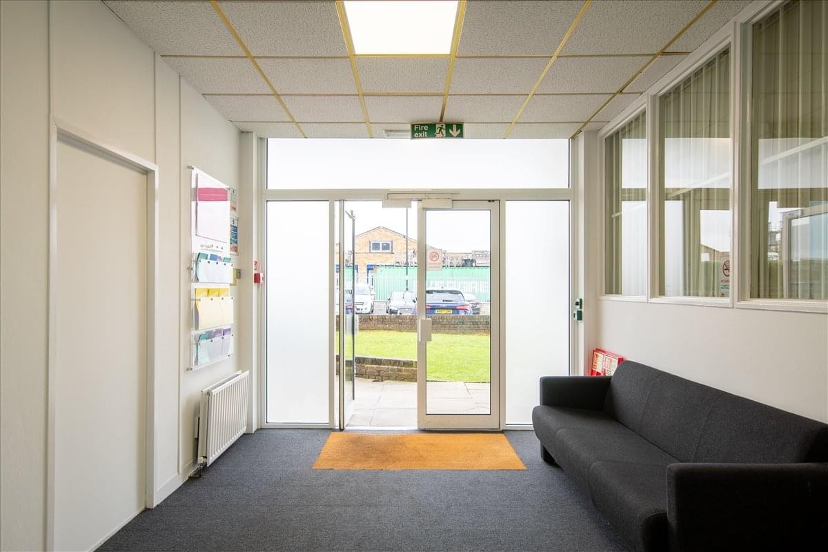Bright reception area at Addington Business Centre featuring a black sofa and large glass entrance doors.
