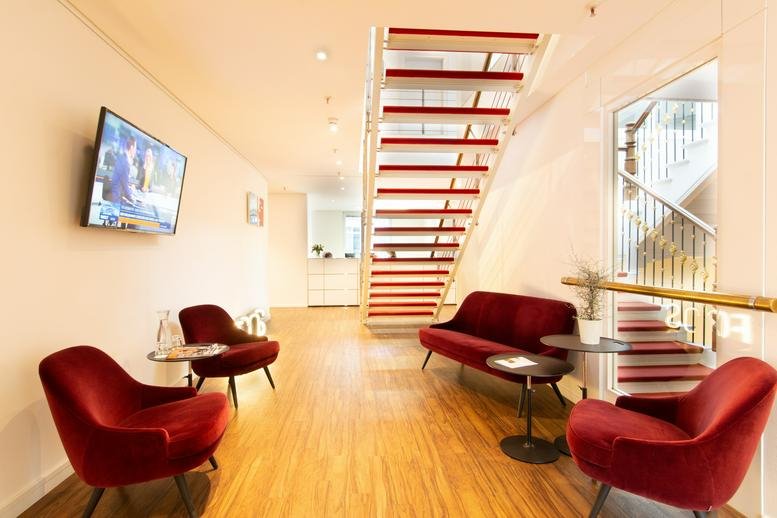 Lounge area with red velvet chairs and modern white staircase.