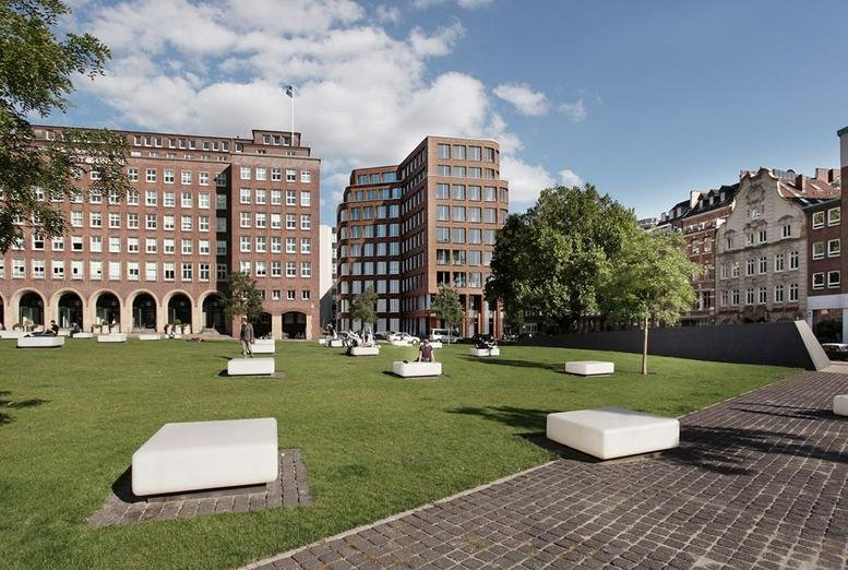 Exterior view of the brick-facade Haus am Domplatz overlooking a green public square.
