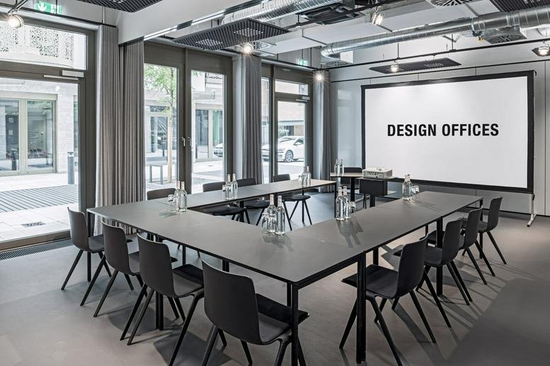 Meeting room at Design Offices Stuttgart Tower featuring a U-shaped table and large projector screen.