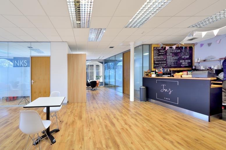 Spacious communal cafe area at Great Michael House with wooden floors and a service counter.