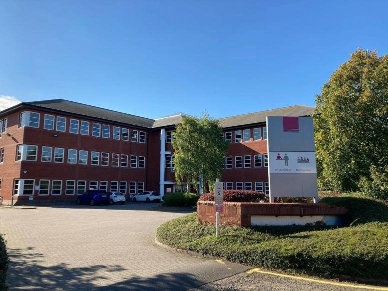 Wide exterior view of the brick office building under a clear blue sky.