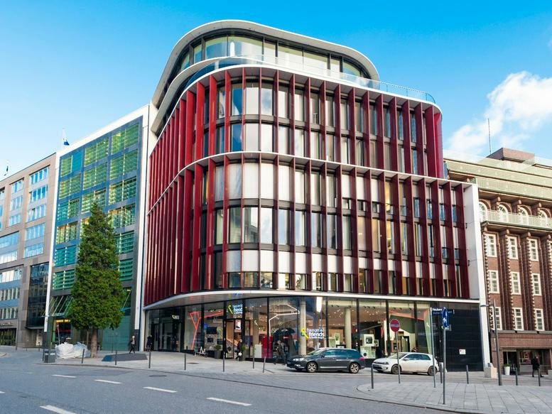Modern exterior of Hohe Bleichen 8 with a distinctive curved red facade and large ground-floor windows.