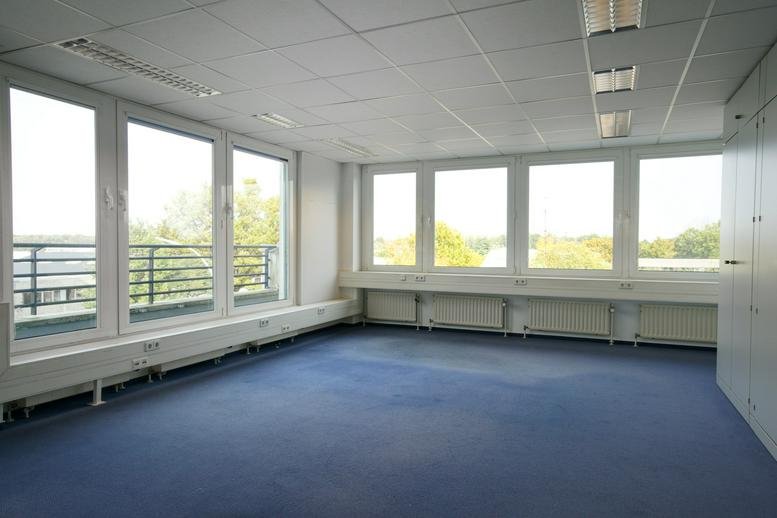 Spacious corner office with multiple large windows overlooking trees.